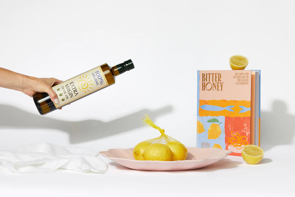 dinner soiree settlement gift items arranged artfully with a hand pouring a bottle of olive oil